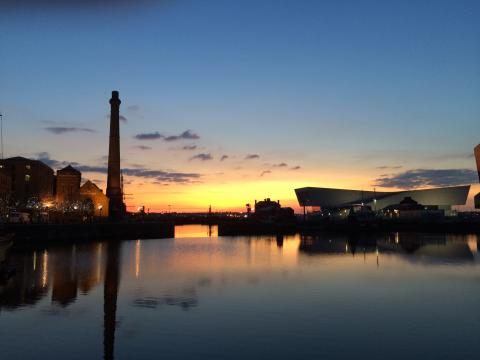 Sunset over a waterfront with building silhouettes and a calm water reflection