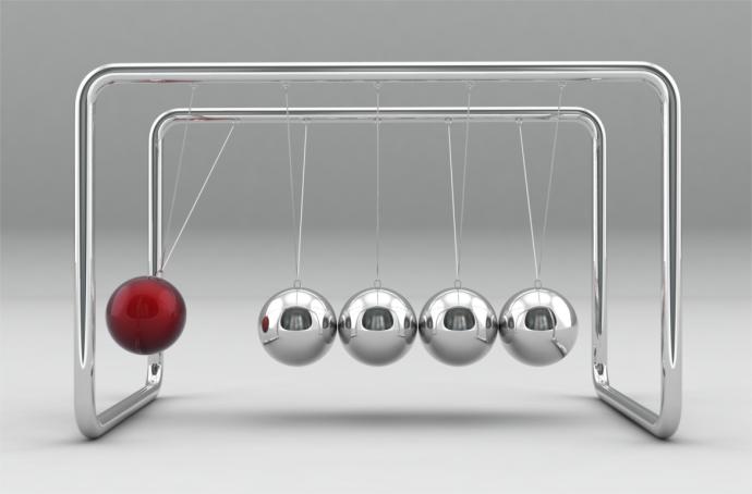 Newton's cradle with five metallic spheres suspended in a row. The leftmost sphere is raised and red, showing potential energy before it strikes the others